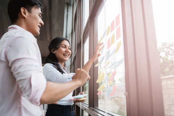 Two individuals pasting sticky notes on the window