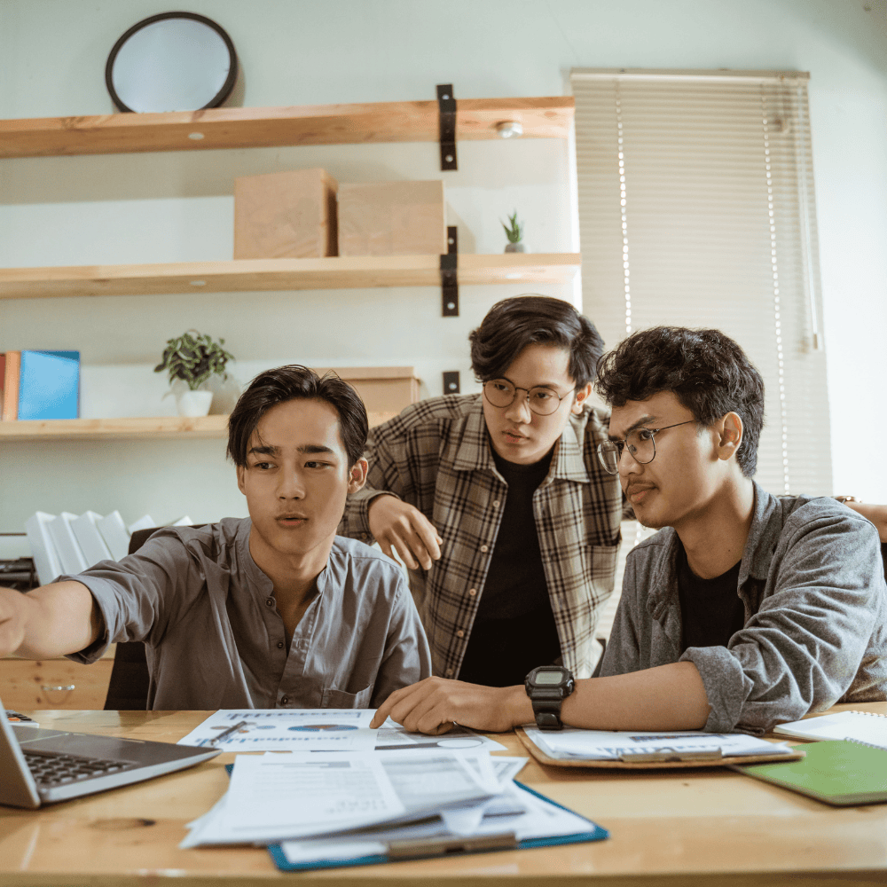 A guy with gray shirt showing is having discussion with his two friends